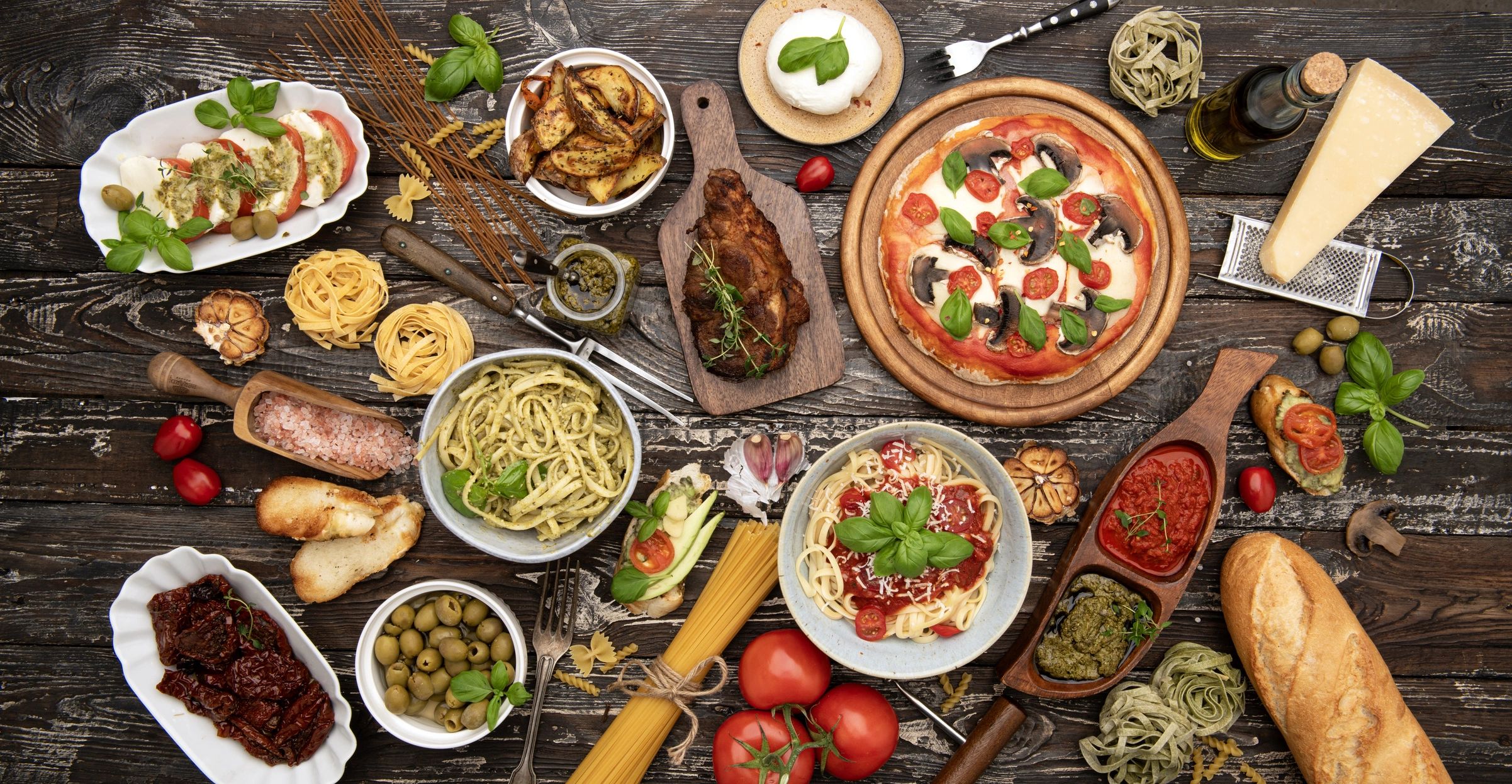 Italian dishes including pasta and pizza on a rustic table